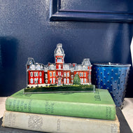 Acrylic cutout of the West Virginia University building, Woodburn Hall  against a blue background.  Original artwork by artist Emily Kurth.
