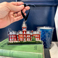 Acrylic ornament of the West Virginia University building, Woodburn Hall  against a blue background.  Original artwork by artist Emily Kurth.