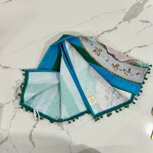 Load image into Gallery viewer, Decorative tea towel with colorful sprinkle cookies on blue and green striped background design on marble surface.
