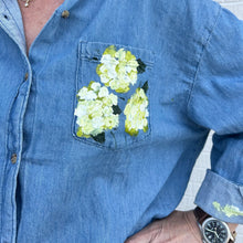 Load image into Gallery viewer, Blue denim shirt with floral painting on the chest pocket.