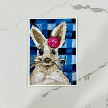 Load image into Gallery viewer, Art print of a rabbit with a pink flower on a blue and white checkered background, on a marble surface.