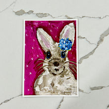 Load image into Gallery viewer, Art print of a rabbit with a blue flower on a pink background, against a marble table.