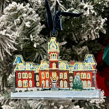 Load image into Gallery viewer, Acrylic ornament of the West Virginia University building, Woodburn Hall with Christmas lights against a Christmas tree background.  Original artwork by artist Emily Kurth.