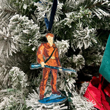 Load image into Gallery viewer, Acrylic ornament of the West Virginia University mascot, the Mountaineer holding his musket against a Christmas tree background.  Original artwork by artist Emily Kurth.