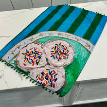 Load image into Gallery viewer, Decorative tea towel with colorful sprinkle cookies on blue and green striped background design on marble surface.
