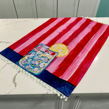 Load image into Gallery viewer, Decorative tea towel with lemonade design on red and pink striped background on marble surface.