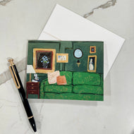 A set of notecards with a painted historic interior design, accompanied by a white envelope and a pen, displayed on a marble surface.  Artwork by artist Emily Kurth.
