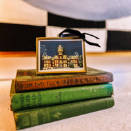 Brass and glass ornament of West Virginia University's Woodburn Hall with Christmas lights by artist Emily Kurth.