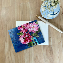 Load image into Gallery viewer, Floral painting on a wooden surface with a vase of rhododendron flowers and a pen.