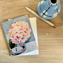 Load image into Gallery viewer, Greeting card with pink hydrangea floral design on a wooden surface with a pen and small vase.