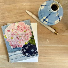 Load image into Gallery viewer, Greeting card with pink hydrangea floral design on a wooden surface with a pen and vase.